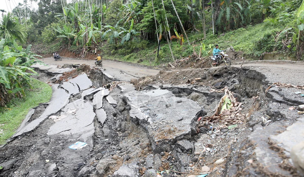 Pengendara sepeda motor melintasi jalan nasional Bireuen–Takengon yang amblas di Bireuen, Aceh, Senin (15/12/2025). Hujan deras akhir November memicu puluhan longsor dan amblas, mengganggu akses menuju Bener Meriah. (Foto: ANTARA FOTO/Irwansyah Putra/tom).